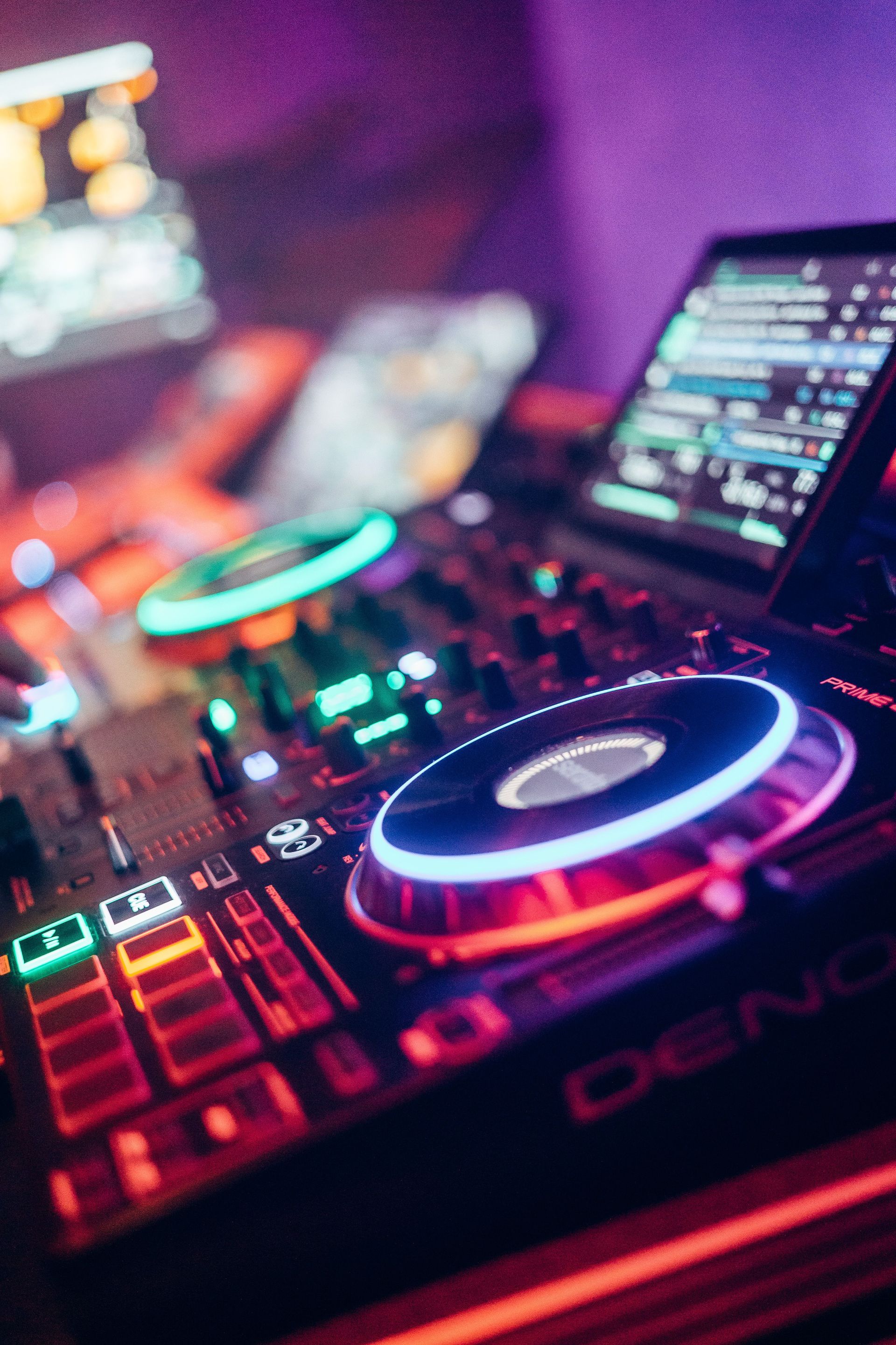 Colorful DJ equipment illuminated with neon lights in a lively nightclub setting.