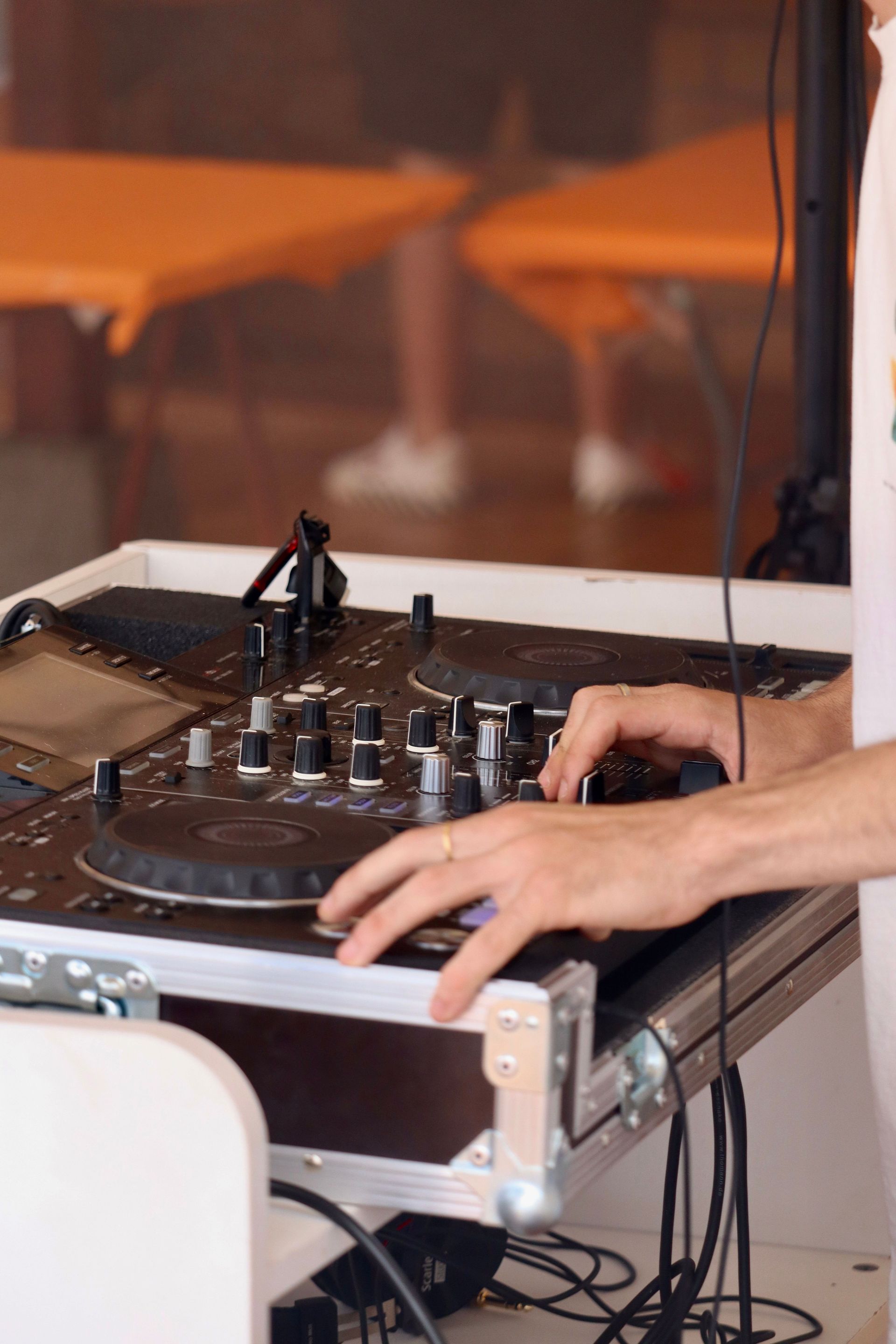 DJ using mixer at an event, showcasing hands on controls for live music mixing.
